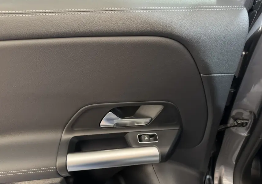 Gros plan sur la porte intérieure côté gauche gris foncé du Mercedes GLA 250 e Business Line 2023 avec poignée alu et bouton de verrouillage.