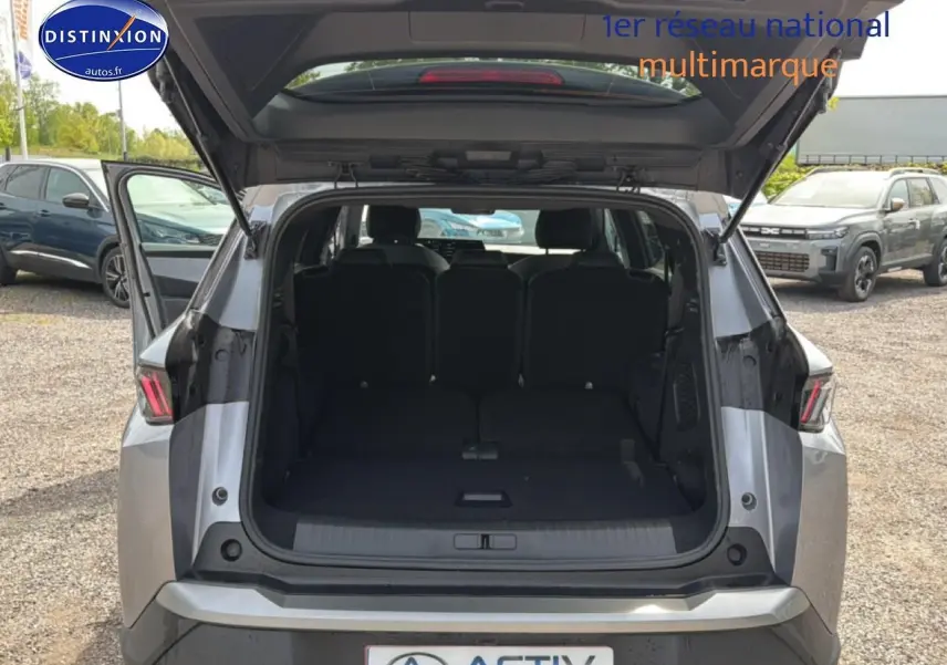Vue arrière ouverte du Peugeot 5008 Hybrid 145 allure e-dcs6 gris artense, montrant le coffre spacieux et les sièges arrière.