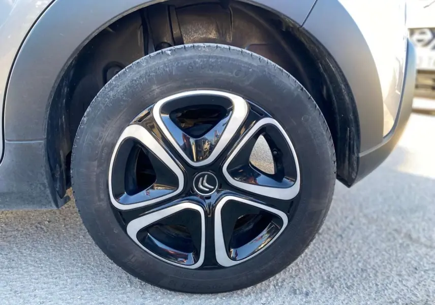 Gros plan sur la roue avant gauche de la Citroën C3 gris Artense avec jante noire et argentée au design moderne.