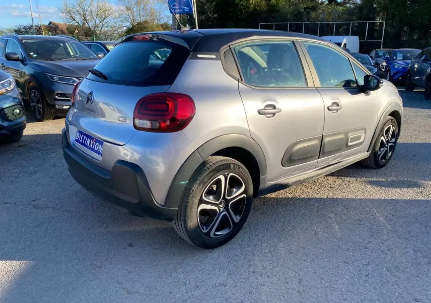 Vue 3/4 arrière droite d'une Citroën C3 gris Artense avec toit noir et jantes alliage distinctives.