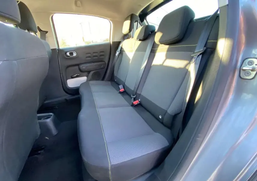 Vue intérieure de la banquette arrière grise de la Citroën C3 2022 côté droit avec ceintures et porte ouvert.