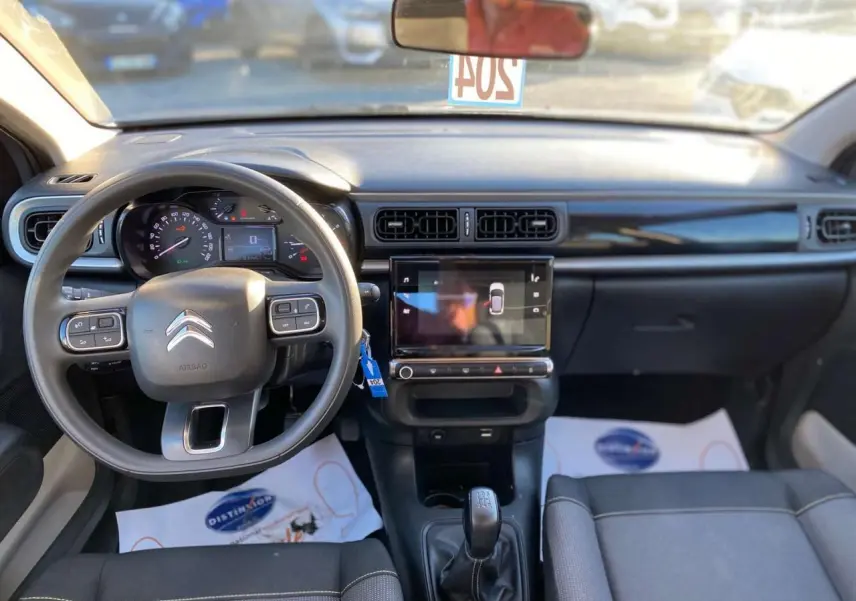Vue intérieure avant du tableau de bord et volant de la Citroën C3 gris Artense avec écran tactile central et boîte manuelle.