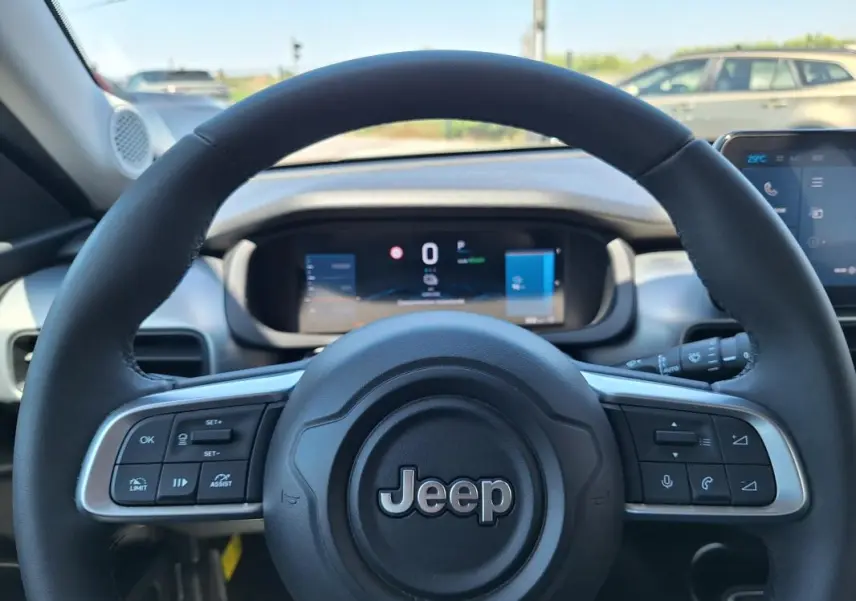 Vue rapprochée du volant noir du Jeep Avenger électrique 2025, avec commandes intégrées et tableau de bord numérique.
