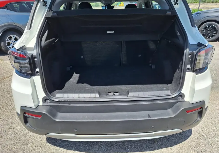 Vue arrière du coffre ouvert d'un Jeep Avenger électrique blanc, mettant en valeur l'espace de chargement.