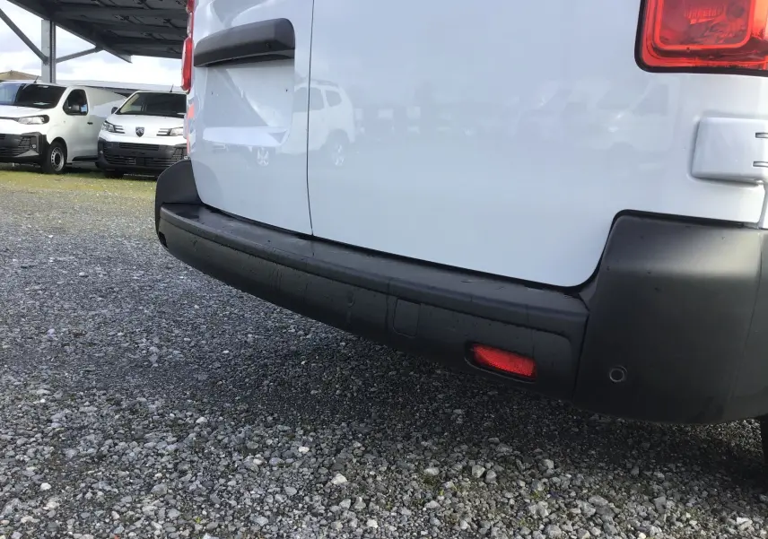 Vue rapprochée de l’arrière droit d’un FIAT Scudo Fourgon blanc, avec pare-chocs noir et feu réfléchissant rouge.