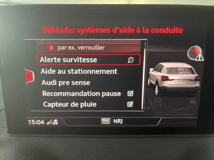Écran multimédia Audi Q2 montrant les options d'aide à la conduite avec illustration d'un SUV gris vu de l'arrière.