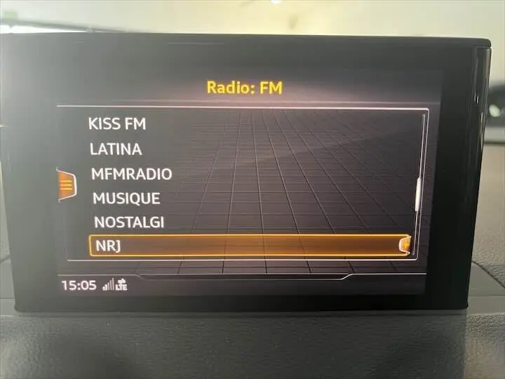 Écran central de l'Audi Q2 affichant la liste des radios FM avec NRJ sélectionnée, intérieur sobre et moderne.