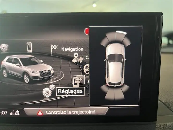 Affichage intérieur du système de navigation montrant une Audi Q2 gris Daytona en 3/4 avant avec alertes de trajectoire active