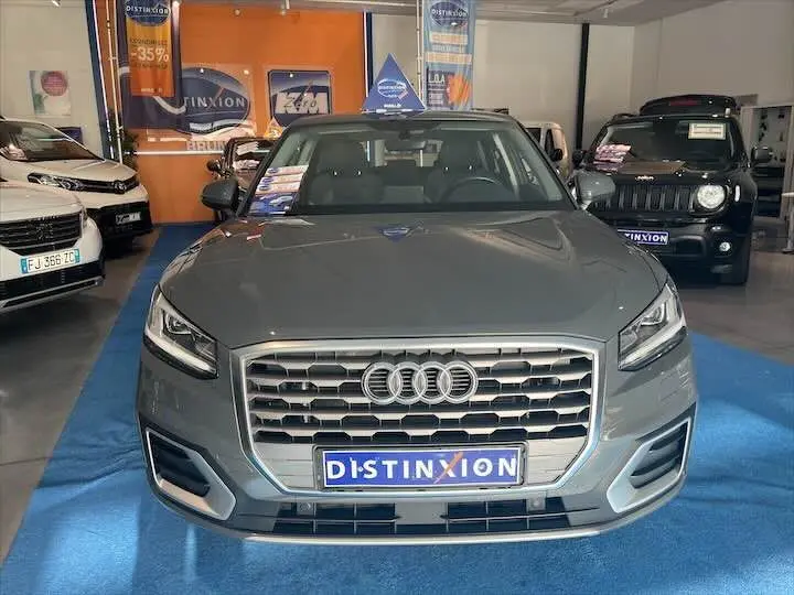 Audi Q2 35 TFSI gris Daytona vue de face en intérieur, avec calandre hexagonale et logo Distinxion visible.