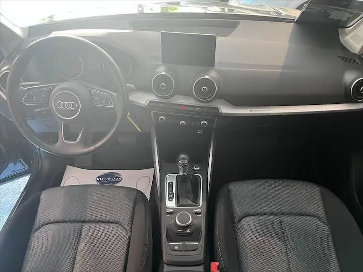 Vue intérieure de l'Audi Q2 2020 montrant le tableau de bord et la console centrale avec volant à gauche et sièges noirs.