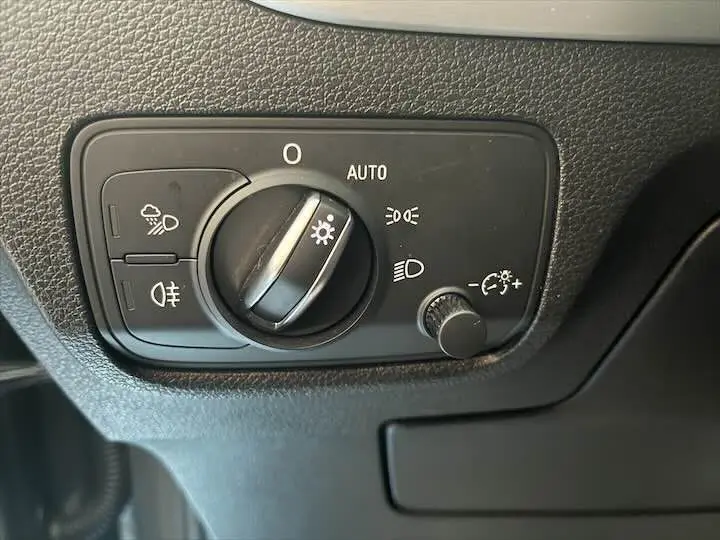 Gros plan sur le bouton de commande des phares de l'Audi Q2 35 TFSI gris Daytona, intérieur côté conducteur.