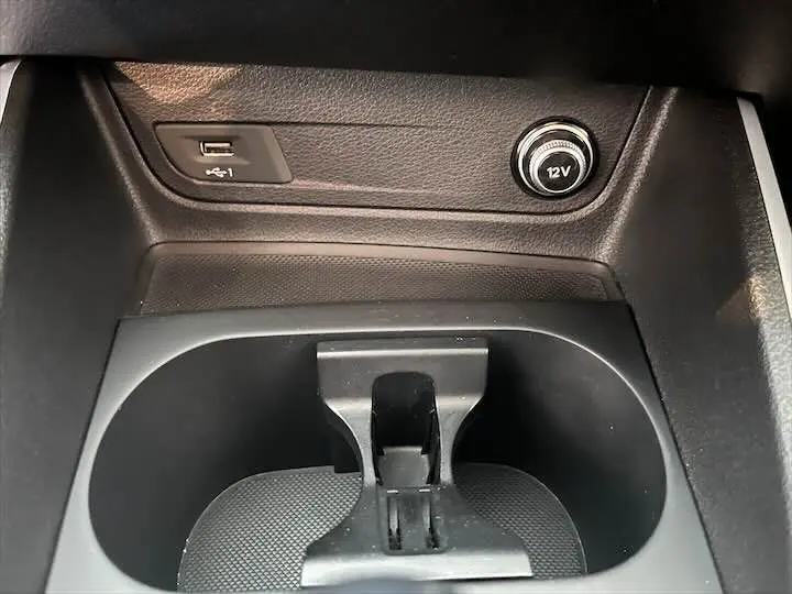 Gros plan sur la console centrale noire de l'Audi Q2 35 TFSI avec prise USB et allume-cigare 12V visibles.