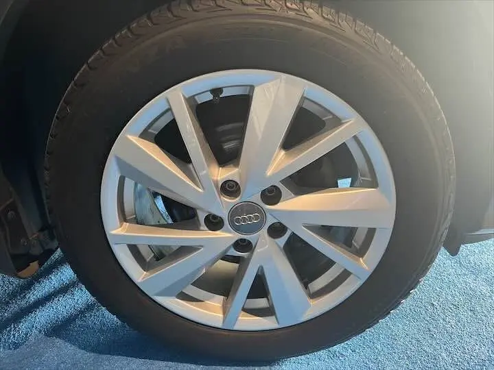 Gros plan sur la jante alliage argentée de l'Audi Q2 35 TFSI gris Daytona, mettant en valeur le logo Audi central.