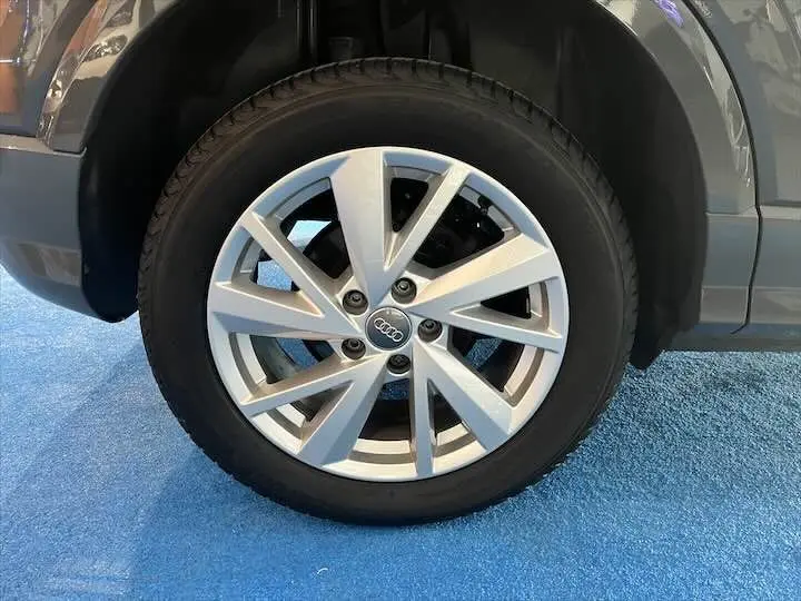 Gros plan sur la roue avant droite d'un Audi Q2 gris Daytona, mettant en valeur la jante alliage à dix branches.