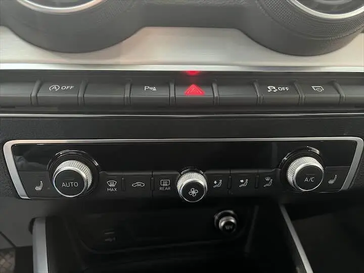 Tableau de bord de l'Audi Q2 35 TFSI 2020 montrant les commandes de climatisation et les boutons de sécurité en gros plan.