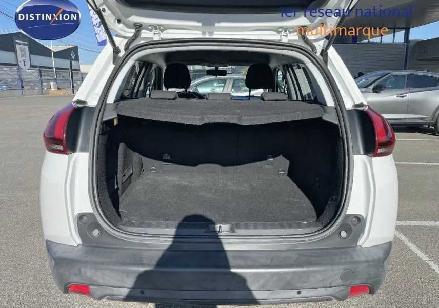 Coffre ouvert d'un Peugeot 2008 blanc vu de l'arrière, montrant l'espace de chargement et la banquette arrière.