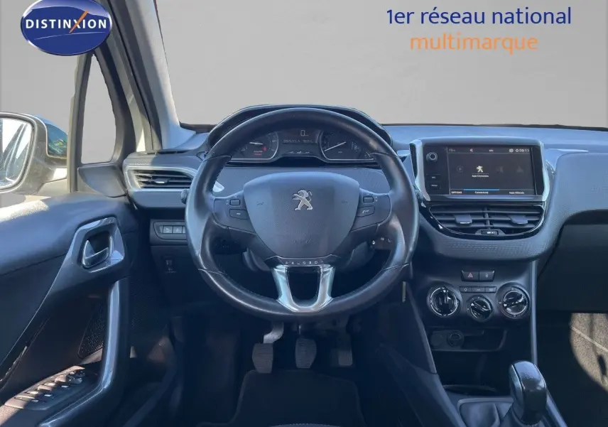 Vue intérieure frontale du tableau de bord et volant noir de la Peugeot 2008 blanche, avec écran tactile et commandes manuelles.