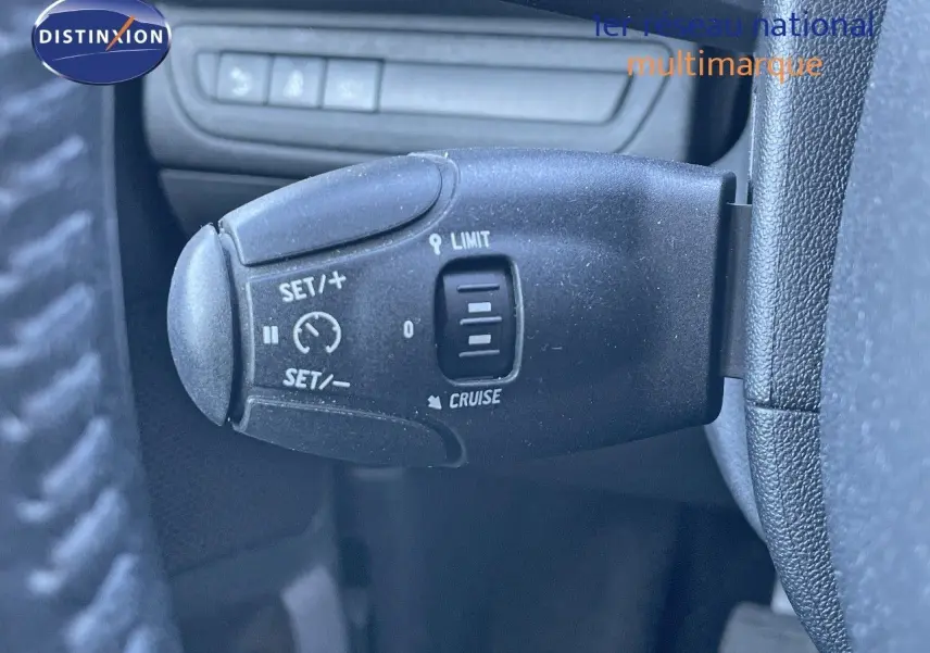 Gros plan sur la commande de régulateur et limiteur de vitesse du Peugeot 2008 blanc de 2017, intérieur côté gauche.