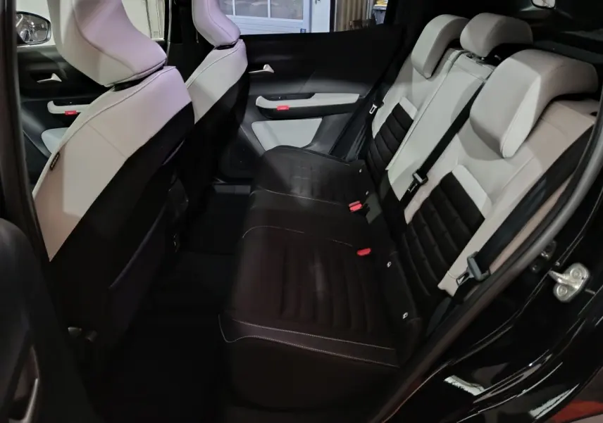 Vue intérieure arrière côté droit de la Citroën C3 hybride 2025, sièges bicolores noir et beige avec ceinture de sécurité.