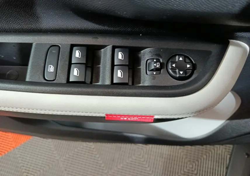 Gros plan sur les commandes de lève-vitres et réglage des rétroviseurs côté conducteur de la Citroën C3 hybride 2025.