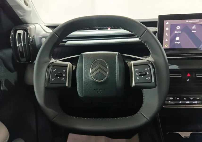 Vue frontale du volant cuir noir de la Citroën C3 Hybride 136 e-DSC6 MAX avec commandes multifonctions et écran tactile visible.
