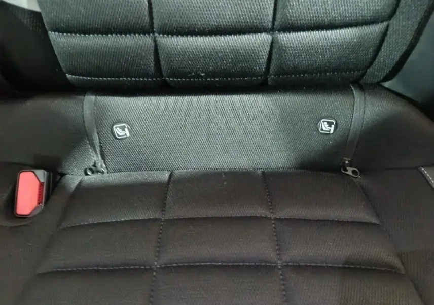Gros plan sur la banquette arrière noire de la Citroën C3 hybride 2025 avec fixation Isofix et boucle de ceinture rouge visible.