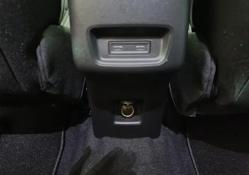 Prise USB et prise 12V vue en gros plan à l'arrière de la console centrale d'une Citroën C3 noire hybride.