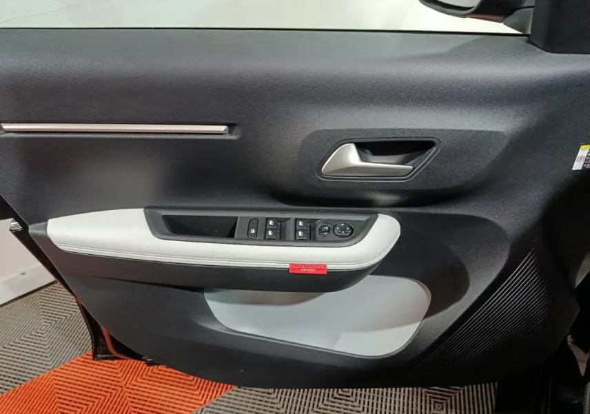 Vue rapprochée de la porte avant gauche noire de la Citroën C3 hybride 2025 avec garniture grise et commandes électriques.