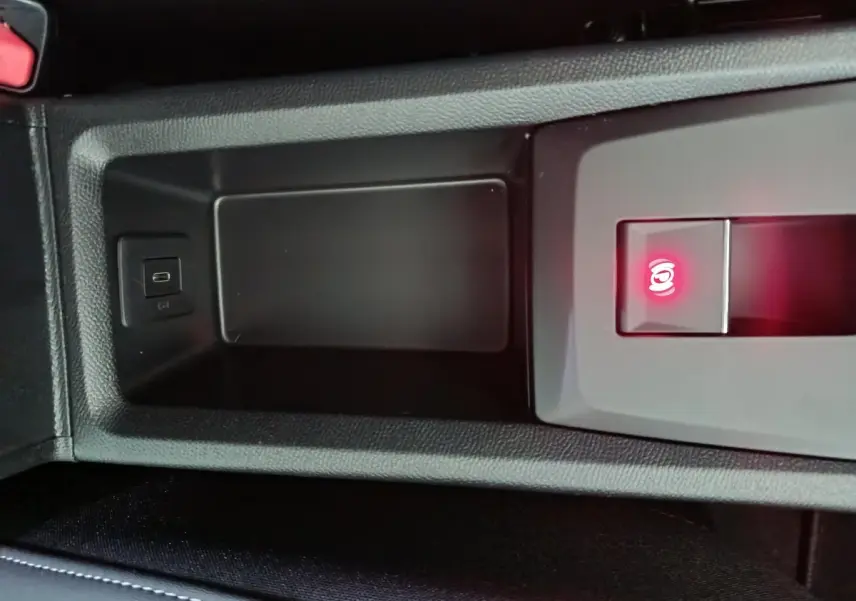 Gros plan sur la console centrale noire de la Citroën C3 hybride 2025 avec frein à main électrique et port USB visible.