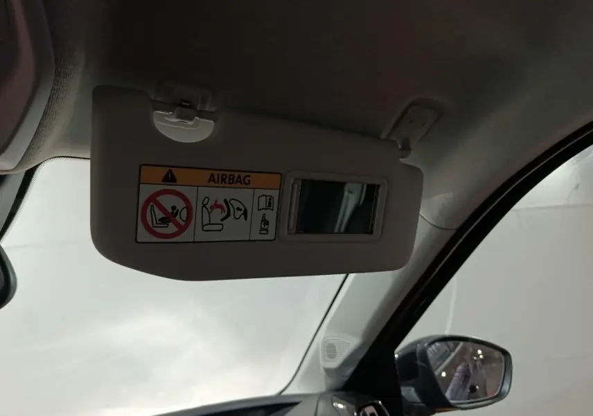 Vue intérieure côté conducteur sur le pare-soleil beige avec miroir et rétroviseur extérieur noir d'une Citroën C3 hybride 2025.