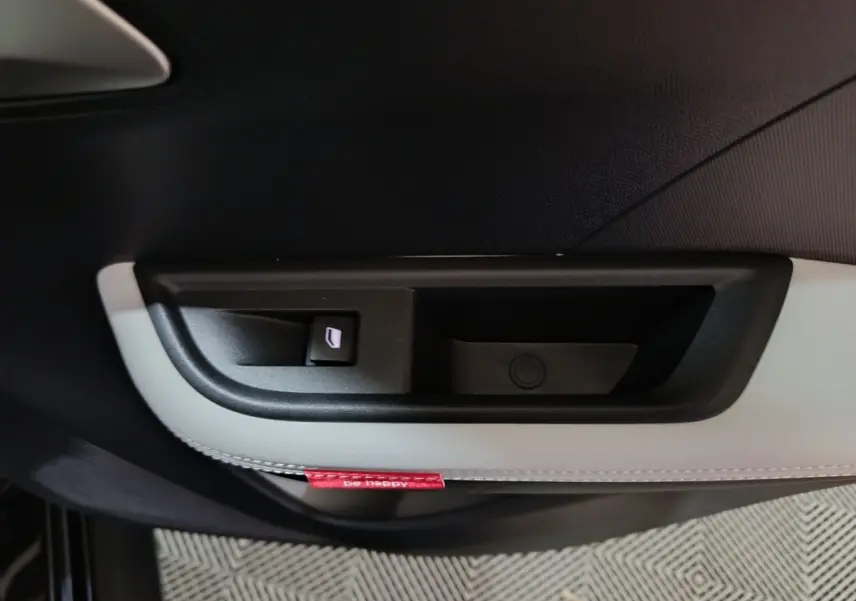 Gros plan sur la commande de lève-vitre côté gauche de la porte intérieure noire et blanche du Citroën C3 Hybride 2025.