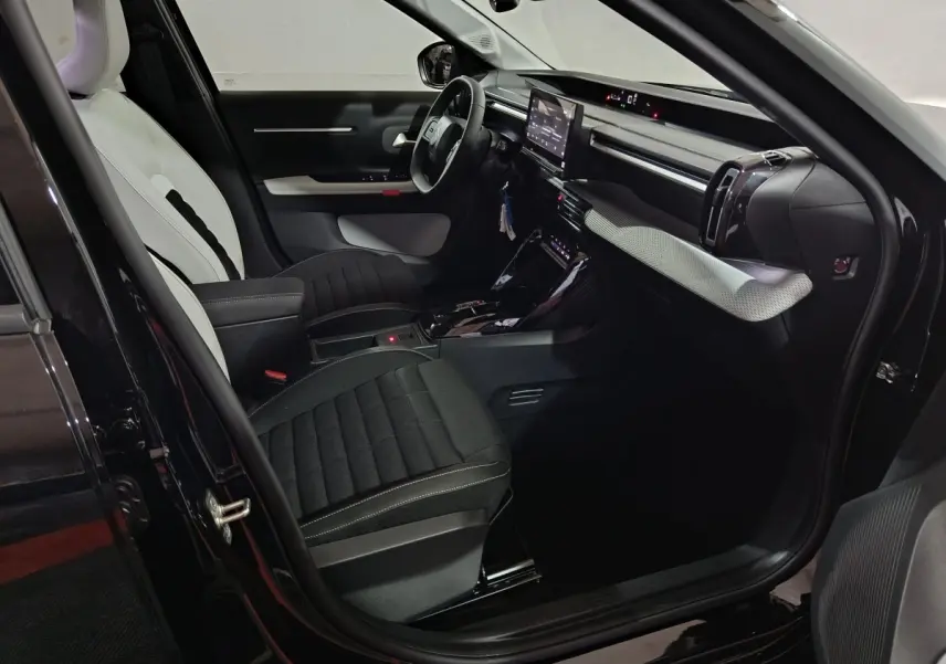 Intérieur avant droit de la Citroën C3 hybride noire 2025 avec sièges bicolores et écran tactile central.