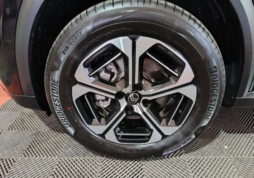 Gros plan sur la roue avant droite d'une Citroën C3 noire, mettant en valeur le pneu Bridgestone et l'aile du véhicule.