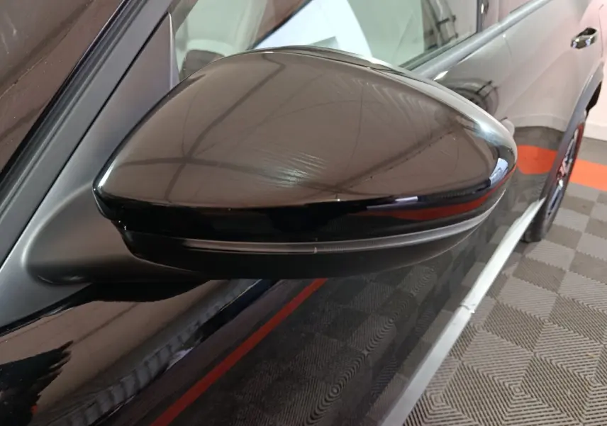 Gros plan sur le rétroviseur droit noir brillant de la Citroën C3 hybride 2025, avec clignotant intégré.