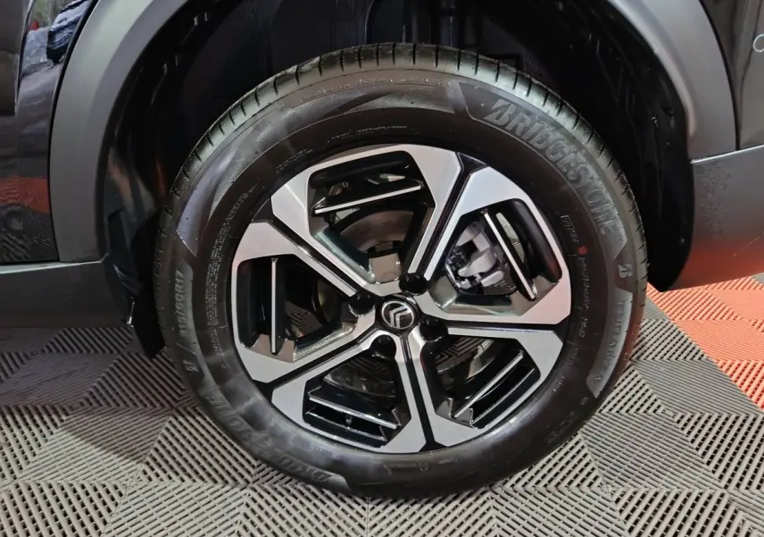 Gros plan sur la roue avant droite noire d'une Citroën C3 Hybride 136 e-DSC6 MAX avec jante alliage bicolore.