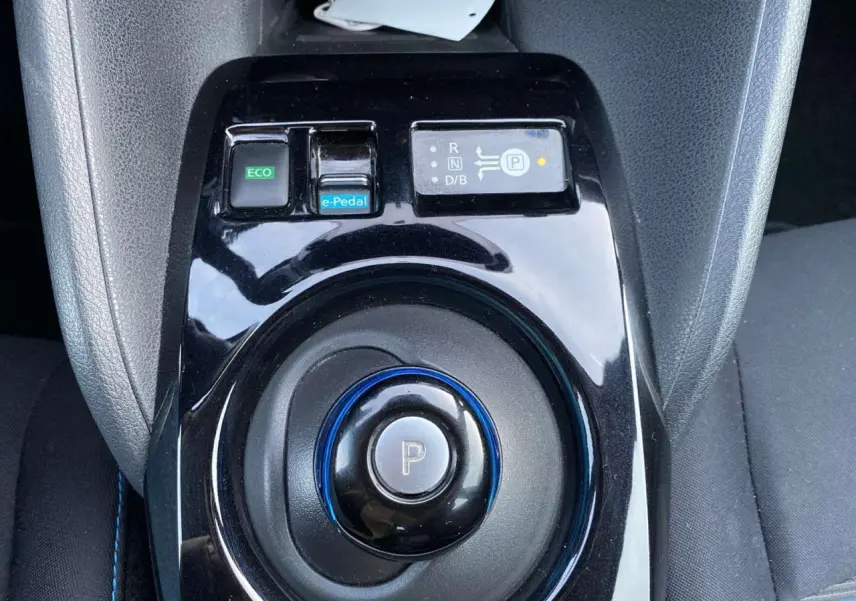 Vue rapprochée de la console centrale noire du Nissan Leaf blanc, avec sélecteur de vitesse circulaire et bouton e-Pedal.