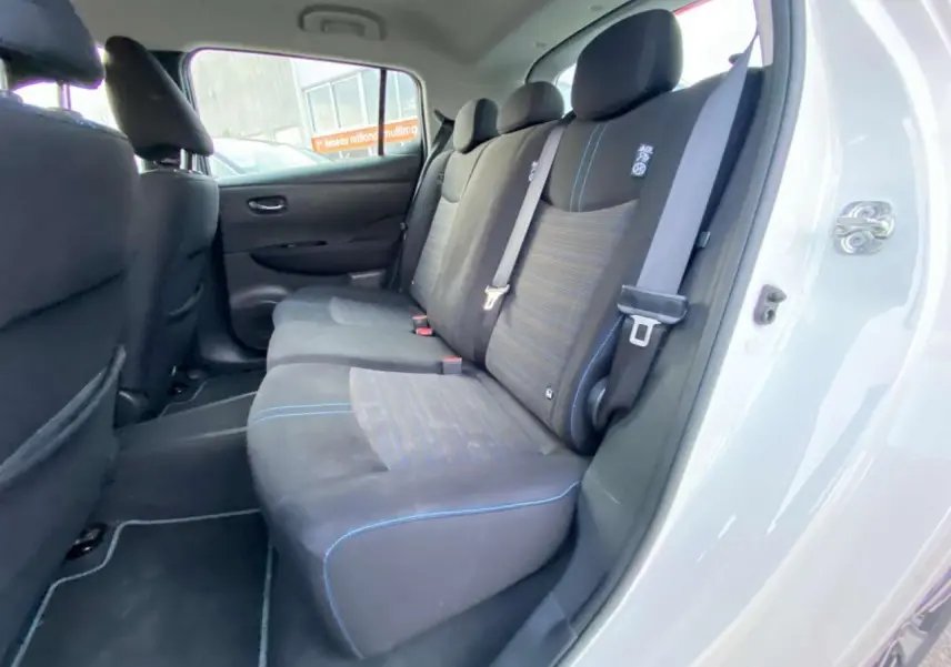 Vue intérieure arrière côté droit du Nissan Leaf blanc 2020, montrant les sièges arrière en tissu noir avec surpiqûres bleues.