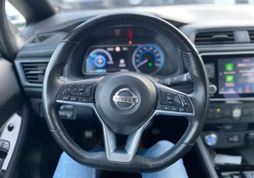 Vue centrée sur le volant noir de la Nissan Leaf 40 kWh 2020, avec tableau de bord et écran tactile en arrière-plan.