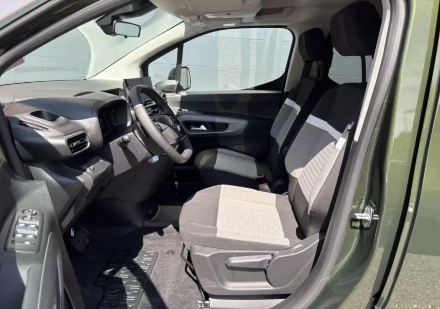 Vue intérieure côté conducteur du Citroën Berlingo Sirkka green 2026, sièges tissu bicolores et volant cuir multifonctions.