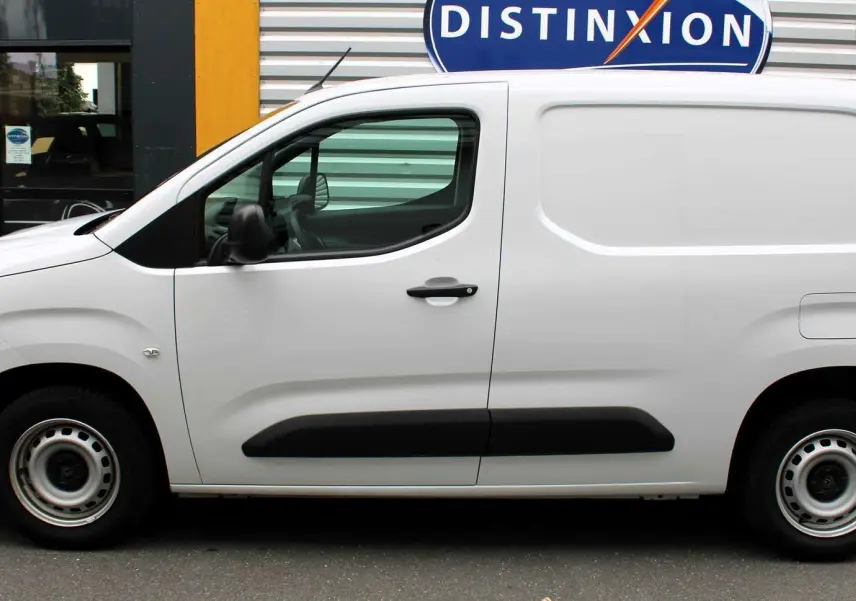 Profil côté gauche du Peugeot Partner Fourgon blanc 2025 avec protections latérales noires et jantes acier simples.