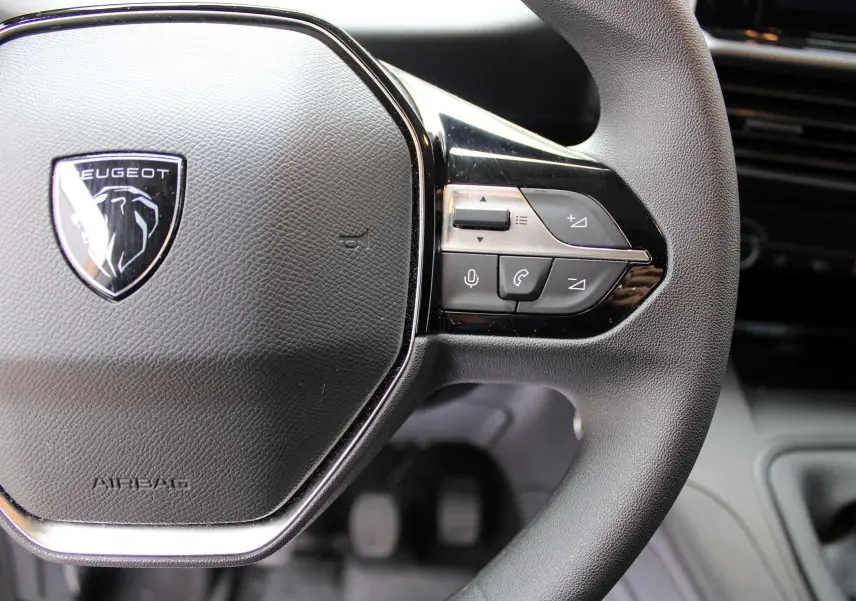 Gros plan sur le volant noir du Peugeot Partner Fourgon 2025 avec commandes intégrées côté droit.