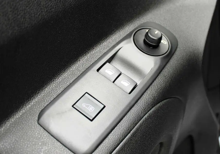 Gros plan sur les commandes de lève-vitres et rétroviseurs sur la porte intérieure noire du Peugeot Partner Fourgon blanc 2025.