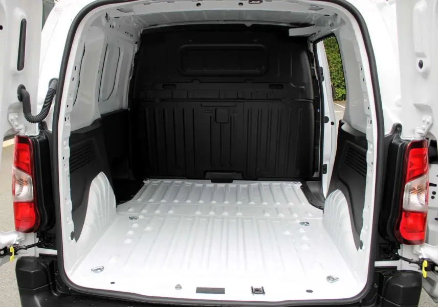 Vue arrière du Peugeot Partner Fourgon blanc 2025 avec portes ouvertes montrant l'espace de chargement vide et les feux arrière rouges.