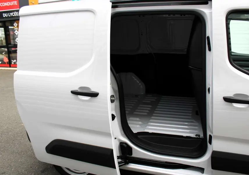 Vue latérale gauche du Peugeot Partner Fourgon blanc 2025 avec porte coulissante ouverte sur l'espace de chargement vide.