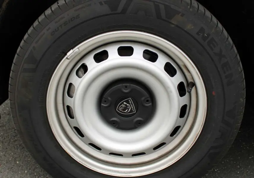 Gros plan sur la roue avant droite du Peugeot Partner Fourgon blanc 2025 avec jante acier et logo Peugeot central.