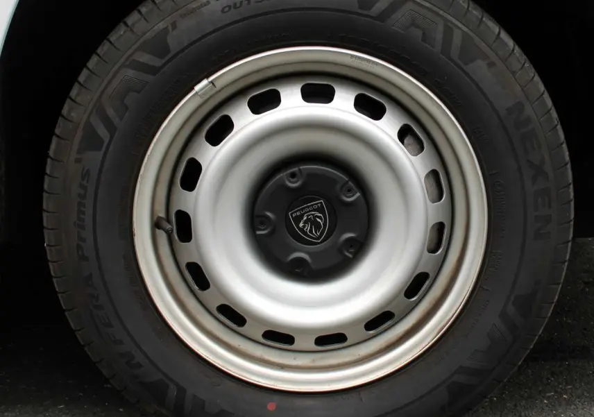 Gros plan sur la roue avant droite du Peugeot Partner Fourgon blanc 2025 avec jante acier et logo lion central.