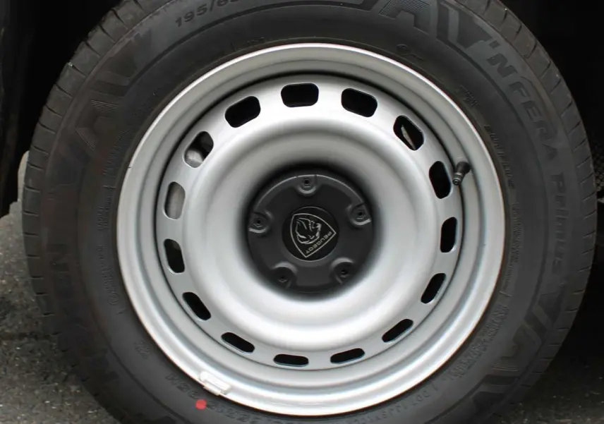 Gros plan sur la roue acier grise avec logo Peugeot du Partner Fourgon blanc, mettant en valeur le pneu et la jante simple.