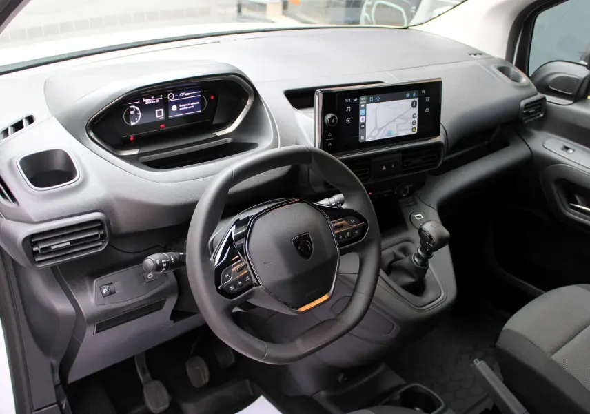 Intérieur du Peugeot Partner Fourgon 2025, vue du poste de conduite avec volant, écran tactile et levier de vitesse manuel.