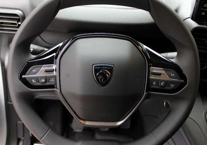 Volant multifonction noir du Peugeot Partner Fourgon 2025 avec commandes intégrées et logo lion central.