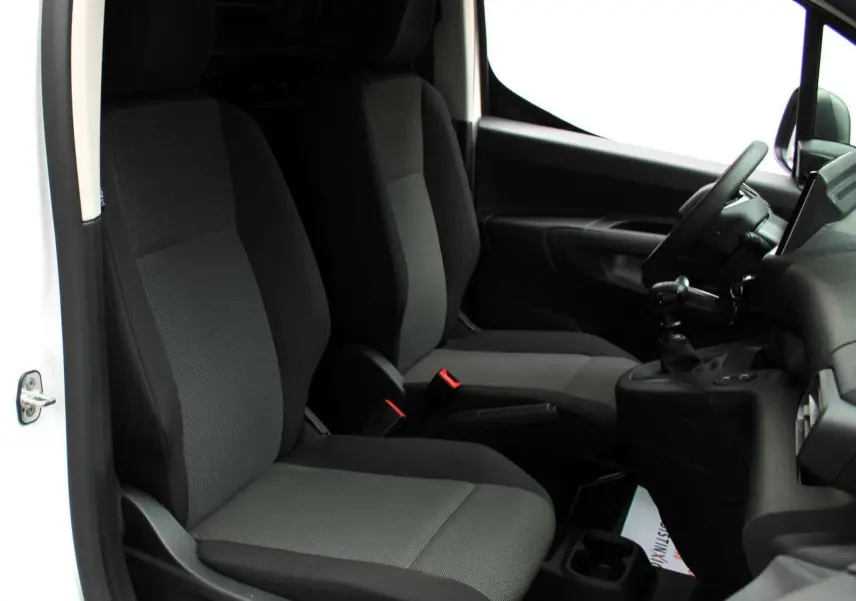 Vue intérieure côté conducteur du Peugeot Partner Fourgon blanc 2025, montrant les sièges avant et le volant.